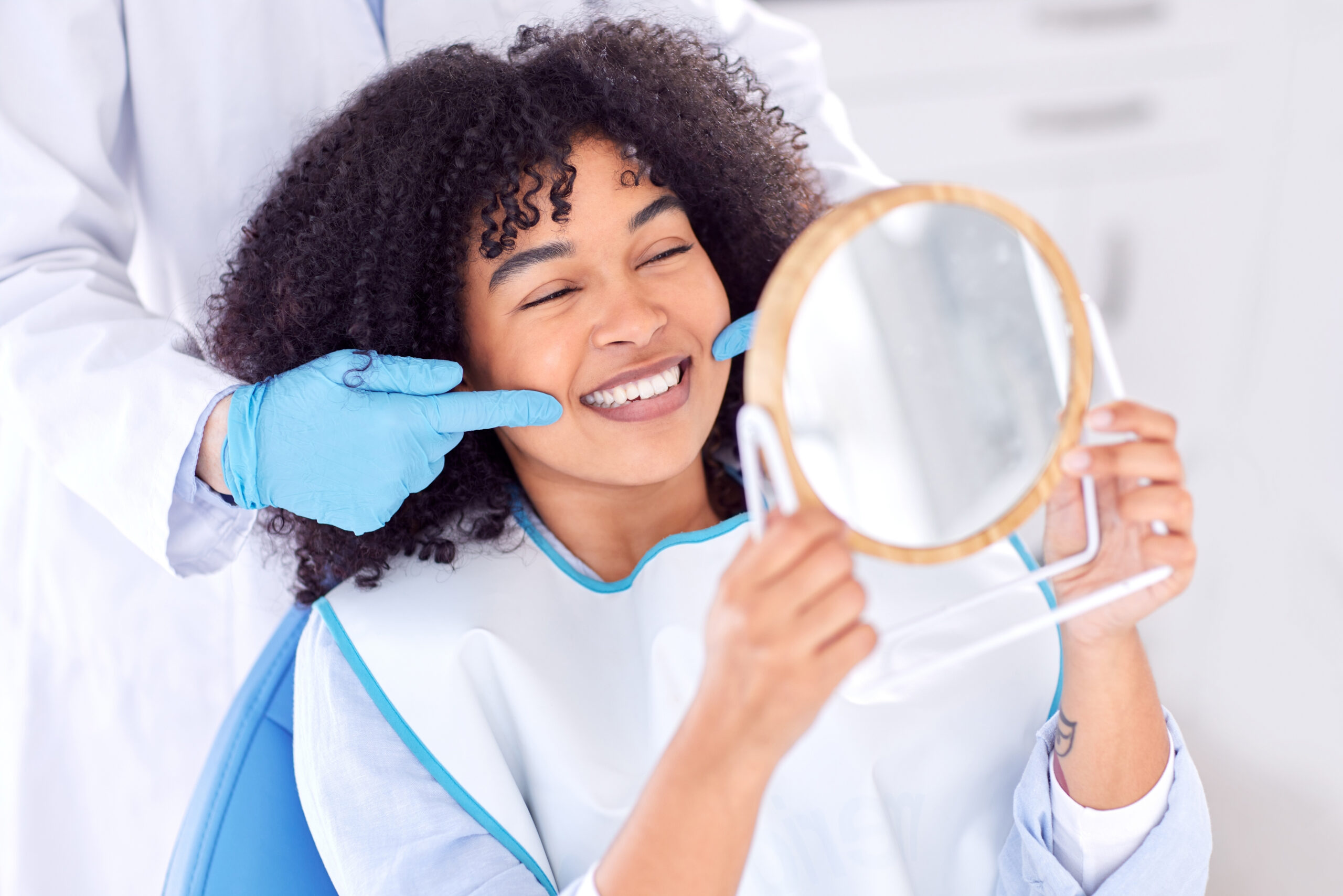 Woman, patient and dentist with mirror for teeth whitening in clinic for dental surgery and results with doctor. People, satisfied and happy on consultation for root canal procedure and oral care.